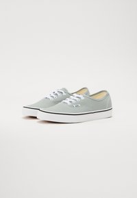 Ljusgröna canvas-sneakers med vita snören, svart kant och gummisulor. Har en rund tå och minimal sömdetalj.