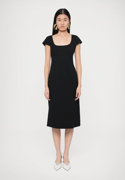 Robe noire jusqu'aux genoux avec un décolleté carré et de courtes manches gigot. Texture lisse, coupe ajustée, avec une fente latérale.