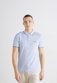 Svijetloplava polo majica s ovratnikom i tri gumba, s crnim obrubom na rukavima i "BOSS" logom na lijevoj strani prsiju.