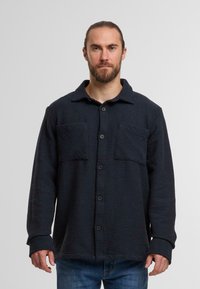 Marineblaues, strukturiertes Button-Up-Shirt mit zwei Brusttaschen, langen Ärmeln und Kragen. Verfügt über ein gewebtes Muster für zusätzliche Tiefe.