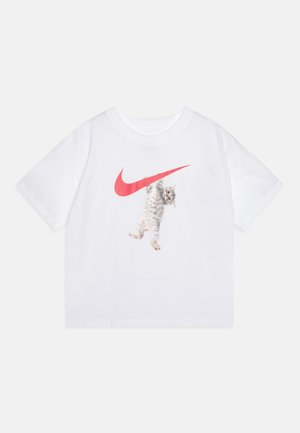 Biały T-shirt z krótkim rękawem z czerwonym logo Nike swoosh i szarym pręgowanym kotkiem wiszącym na logo na przedzie pośrodku.