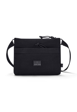 Black fabric crossbody bag with a rectangular shape, adjustable strap, cinch closure, and a small brand logo patch.