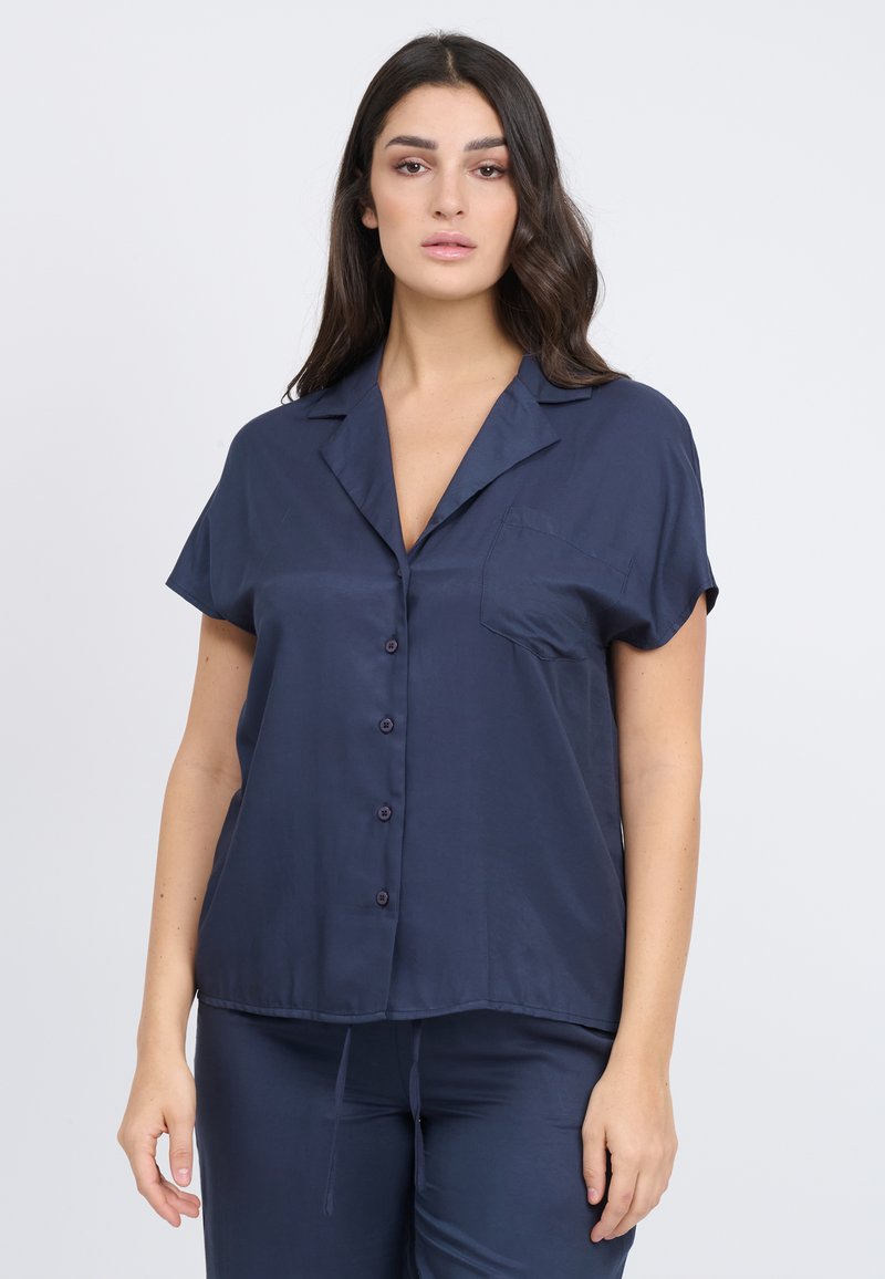 Camicia azzurra a maniche corte con colletto, texture liscia e tasca sul petto, realizzata in tessuto leggero.