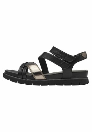 Black leather sandals with metallic accents, featuring cross straps and a thick black rubber sole for added comfort and support.