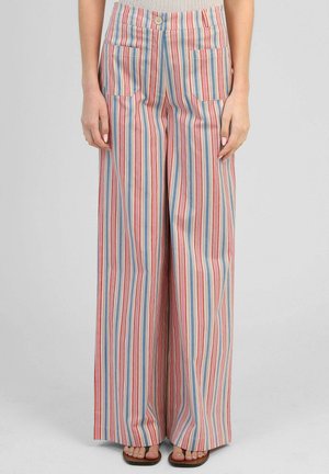 Personne portant un pantalon taille haute, jambes larges, avec des rayures verticales rouges, bleues et roses, poches avant et une fermeture à un bouton.