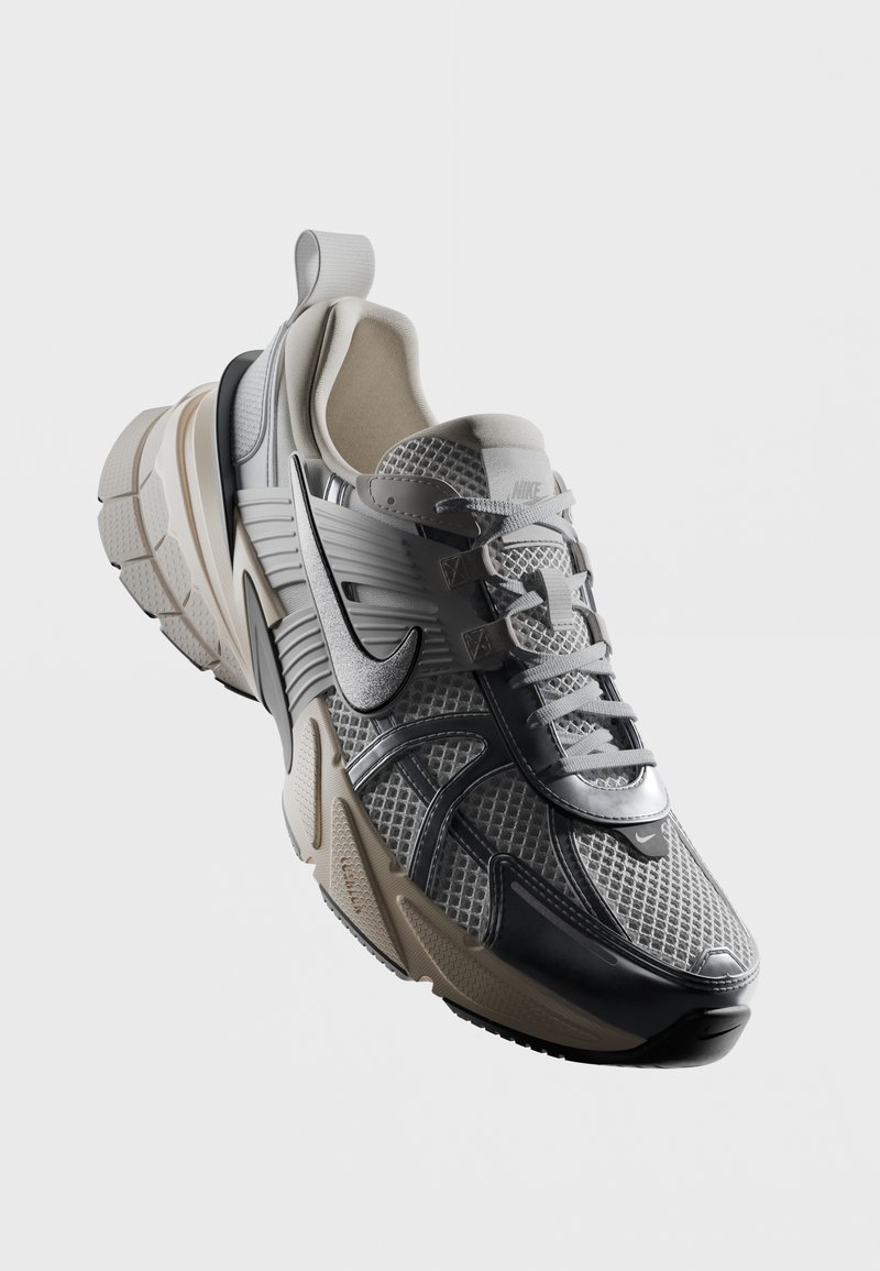 Zapatilla deportiva con parte superior de malla en gris y negro, suela de goma, media suela gruesa y acolchada, y logotipo destacado de Nike en el lado.