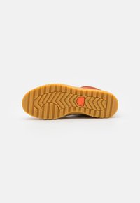 Rubberen sneakerzool met een zigzagloopvlak. De basis is tan met oranje accenten en textuurgebieden voor grip.
