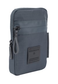 Grijze stoffen zak met een textuur oppervlak, ritssluiting en geweven trekband. Bevat een zwart logo label en een contrasterend streepdessin.