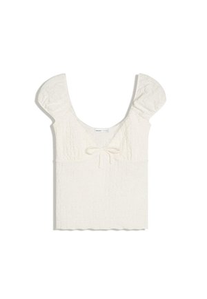 Witte getextureerde cropped top met korte pofmouwen, een ronde hals en een klein strikdetail aan de voorkant.