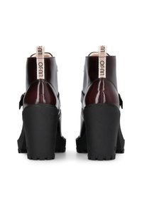 Bordeauxfarbene Lacklederabsätze mit dicken schwarzen Gummisohlen, in Knöchelhöhe und einem Stoffzugband. Mit einem seitlichen Schnallen-Detail.