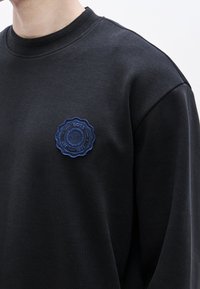 Μαύρο φούτερ με ριμπ λαιμόκοψη και μπλε κεντητό σήμα με κυκλικό σχέδιο, με την επιγραφή "BOSS EST 1971".