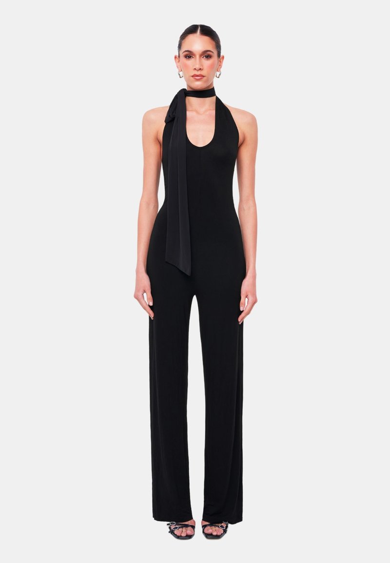 Zwarte halter-jumpsuit in een soepele, rekbare stof. Hij heeft een diepe halslijn, een lange strik bij de hals en wijde broekspijpen.