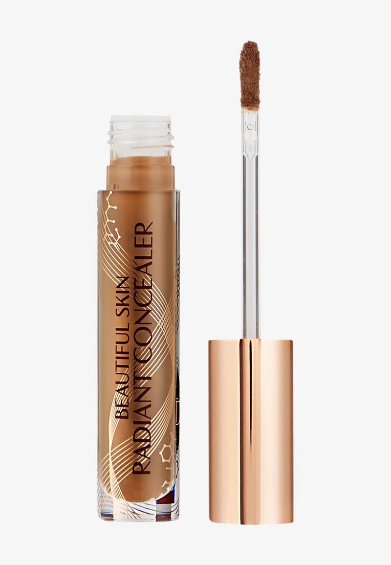 Brown liquid concealer in a clear tube with elegant gold accents; features a clear applicator with a soft, fluffy tip for precise application.