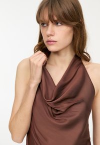 Vínová halter top s volánovým výstřihem, vyrobená z hladké tkaniny. Má bezrukávový design a jemný lesk. Elegantní a přiléhavý silueta.