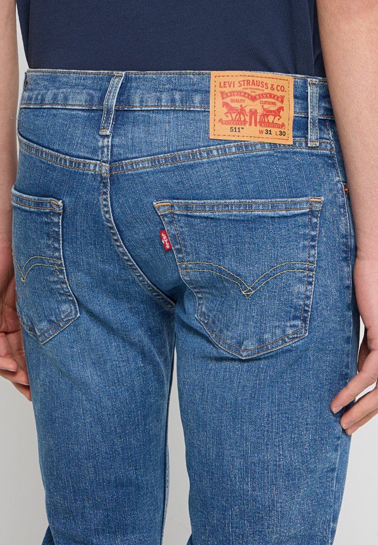 Jeans de mezclilla azul con corte recto, que cuentan con un parche de cuero con la etiqueta "Levi Strauss & Co." y dos bolsillos traseros con detalles de costura.