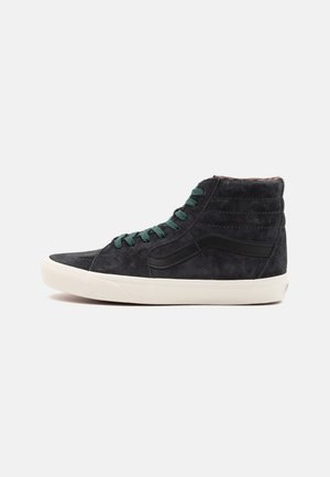 Svarte svette høye sneakers med grønne snøringer og en hvit gummisåle. Har sidestriper og subtil tekstur på overdelen.