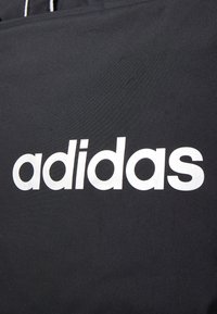 Black fabric with a smooth texture featuring a prominent white "adidas" logo in bold, sans-serif font. Simple and minimalistic design.