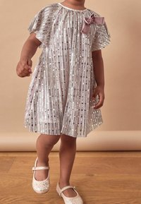 Skimrande silverrandig klänning med korta svävande ärmar och en rosa sammetssnörning, i kombination med glittriga ljusrosa skor.