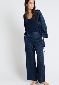 Marineblauwe pyjama set met een losse top en wijde broek met een groen patroon, gemaakt van zachte, lichtgewicht stof.