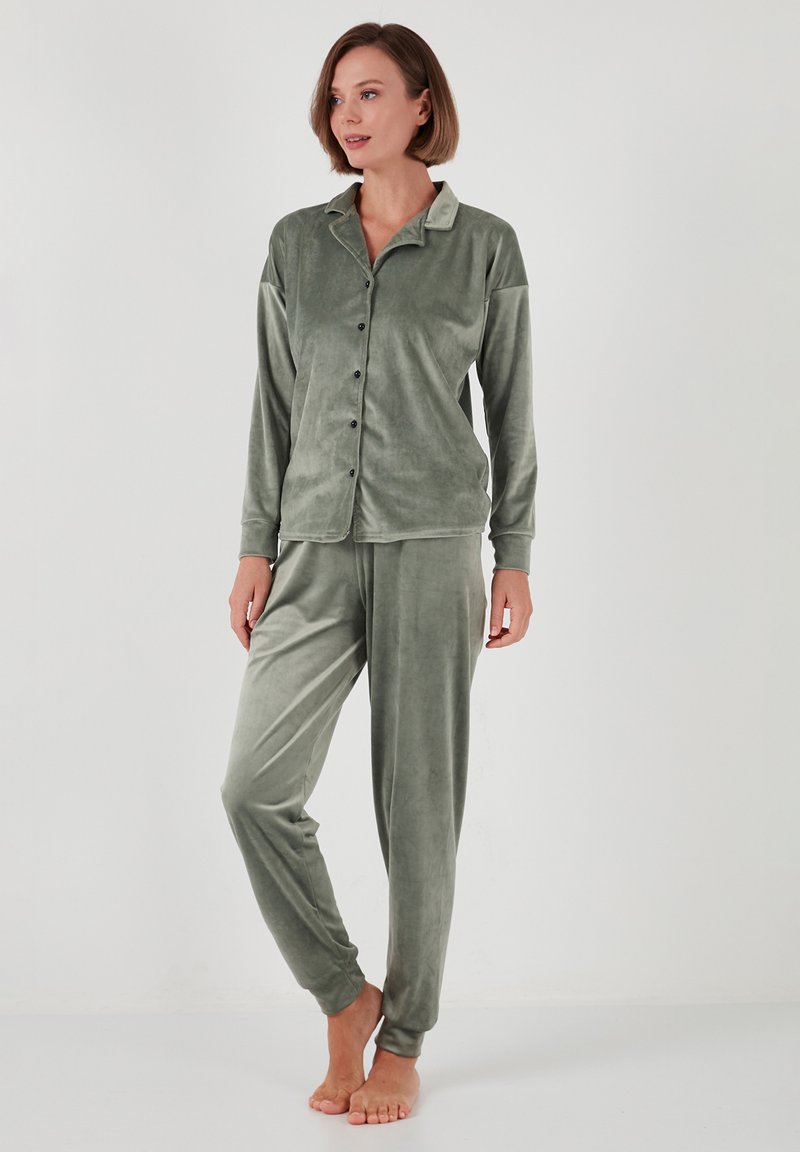 Conjunto de pijama de terciopelo verde con mangas largas, parte superior abotonada y pantalones con puños, que presenta una textura suave y un ajuste relajado.