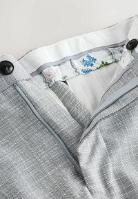 Grau strukturiertes Gewebe mit einem glatten Innenfutter, das florale Muster zeigt, Knopfverschluss und verdecktem Reißverschluss.