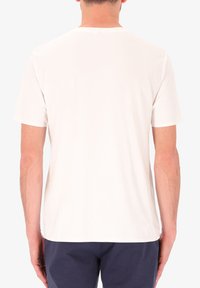 T-shirt bianco con maniche corte, scollatura rotonda, texture liscia e vestibilità regolare, visto dal retro. Nessun motivo o dettaglio visibile.