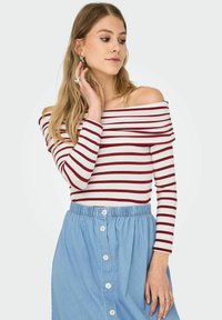 Stripet off-shoulder top i hvid og bordeaux med lange ærmer, parret med en lys blå denimnederdel med frontknaplukning.