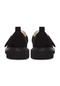 Et par sorte slip-on sko med tykke såler og synlig beige pelsfor, vist fra bagsiden på en hvid baggrund.