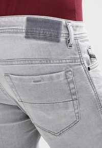 Ljust grå denimjeans med en bakficka, subtila blekningar och sömnadsdetaljer. Elastisk midja med en slät textur.