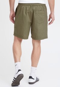 Rohelised puuvillased lühikesed püksid kummist vöökohaga, küljetaskute ja tagataskuga. Muster on ühtlane, lõige lõdvestunud ja pikkus keskmise reie tasemel.