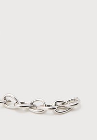 Τμήμα βραχιολιού με αλυσίδα σε ασημί απόχρωση με χοντρά, επιμήκη οβάλ και σταγόνα σχήματα σε λευκό φόντο.