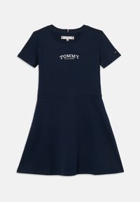 Svetlomodré tričko šaty vyrobené z bavlny, s okrúhlym výstrihom, krátkymi rukávmi a vyšívaným logom na hrudi. Riasená sukňa.