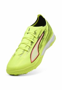 Gult atletiksko med en tekstureret overflade, sorte og røde accenter, et stilfuldt design og en fleksibel sål. Har seks snørehuller.