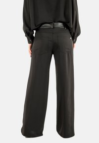 Pantaloni neri a gamba larga con una texture liscia, dotati di due tasche posteriori, una vita aderente e una cintura elegante.