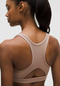 Helle beige Sport-BH mit Racerback-Design, glänzender Textur und Cut-Out-Details auf der Rückseite. Verstellbare Träger.