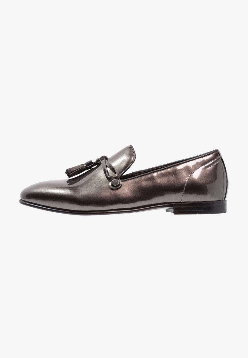 Mocassin pour homme en métal gris brillant, à bout pointu, avec détail de bride à glands et petit talon empilé, présenté en profil latéral.