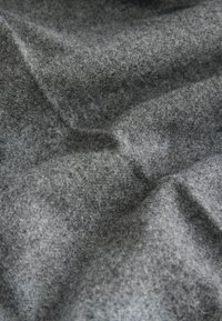 Gray felt fabric with a soft, textured surface, featuring subtle variations in tone and slight plushiness, suitable for various applications.