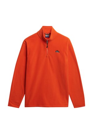 Pomarańczowy polarowy sweter z wysokim kołnierzem, półzapięciem na zamek błyskawiczny oraz małym czarnym logo po lewej stronie klatki piersiowej, z długimi rękawami i gładką fakturą.