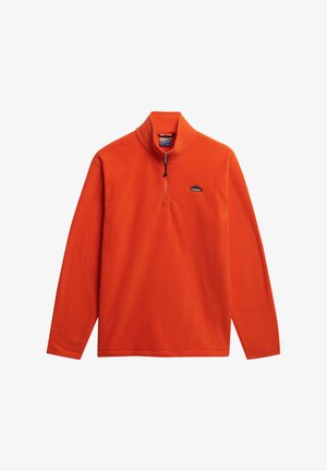 Pomarańczowy polarowy sweter z wysokim kołnierzem, półzapięciem na zamek błyskawiczny oraz małym czarnym logo po lewej stronie klatki piersiowej, z długimi rękawami i gładką fakturą.