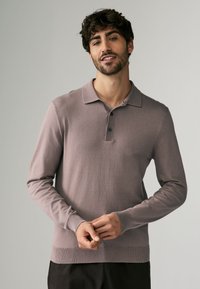 Langarm polo-shirt in gedempt lavendel, gemaakt van zachte stof, met een drieknoopsluiting en geribde manchetten en zoom.