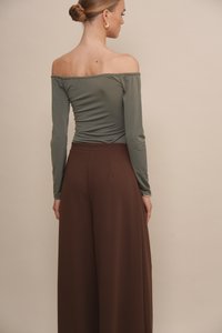 Bluzka w kolorze oliwkowym typu off-the-shoulder z długimi rękawami w połączeniu z brązowymi spodniami o wysokim stanie i szerokich nogawkach, prezentującymi gładką fakturę i zwiewny fason.