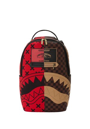 Mochila con diseño dividido, roja con patrón de X negra y patrón de cuadros marrón, con gráfico de boca de tiburón y etiqueta de edición limitada.