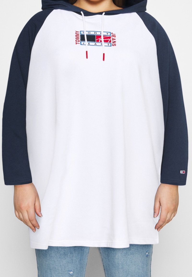 Felpa con cappuccio, corpo bianco e maniche raglan blu navy. Presenta un logo Tommy Jeans ricamato in rosso e blu. Tessuto misto cotone.