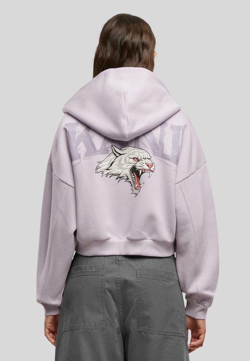 Felpa cropped lilla con grafica di una tigre bianca ruggente sul retro, arricchita da un testo sopra. Tessuto morbido e design dalla vestibilità rilassata.