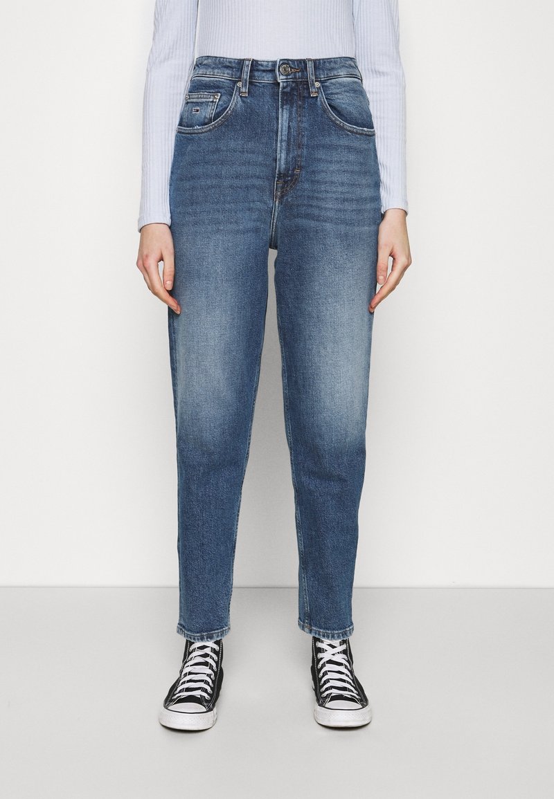 Ljusblå jeans med avslappnad passform, hög midja och minimal blekning. Matchas med svarta högskaftade sneakers och en ribbad långärmad topp.