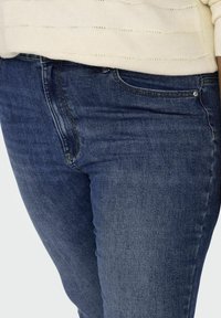 Skinny denim jeans in dark blue, featuring five-pocket styling, subtle fading, and a smooth texture. Pairing with a light-colored sweater.