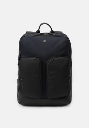 Navy and black nylon backpack with two front zippered pockets, a top handle, and adjustable padded shoulder straps. Minimalist design.