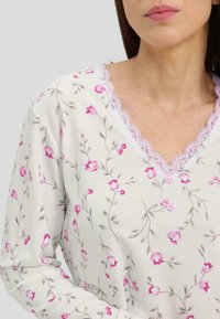 Camisón floral de algodón suave, con un fondo crema y patrones de flores rosas, borde de encaje en el escote y detalles de botones.