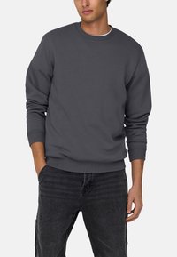 Grau meliertes Crewneck Sweatshirt aus Baumwollmischgewebe mit Rippbündchen und Saum, das eine entspannte Passform und eine glatte Textur bietet.