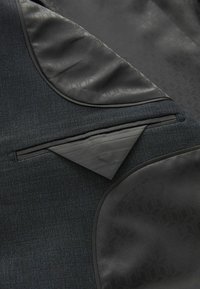 Schwarzer Textilblazer aus strukturiertem blau-grauen Stoff mit satinierter schwarzer Innenauskleidung, ausgestattet mit einer dreieckigen Tasche und glatten Akzenten.